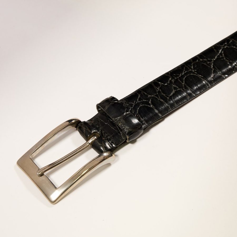 Detail of the buckle of a black crocodile-print belt